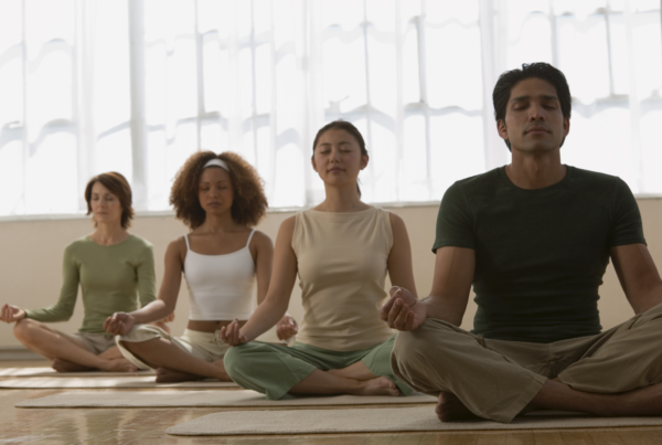 Meditation - 4 people sitting on the floor lotus style, eyes closed with hands in various mudras