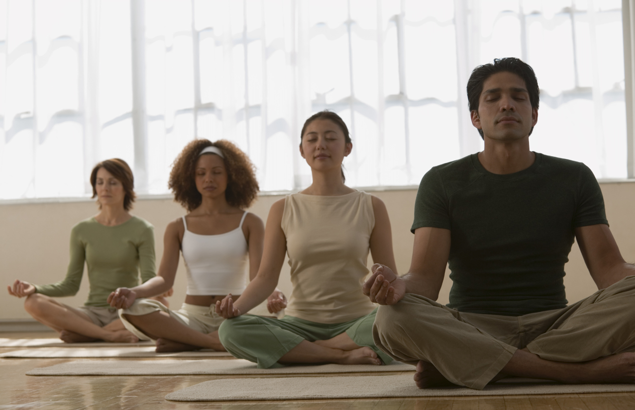 Meditation - 4 people sitting on the floor lotus style, eyes closed with hands in various mudras