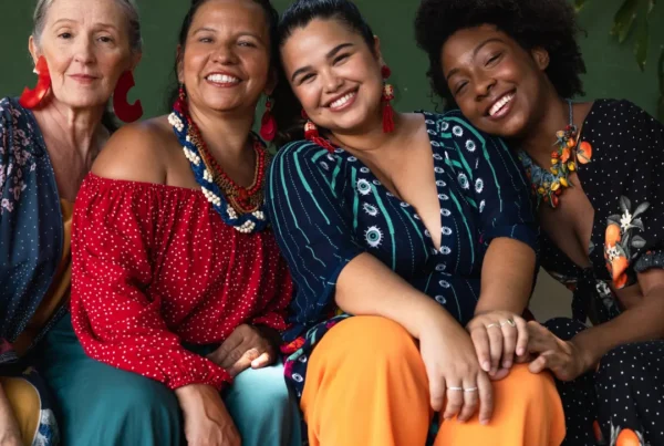 Four diverse women sit and smile together, radiating positivity