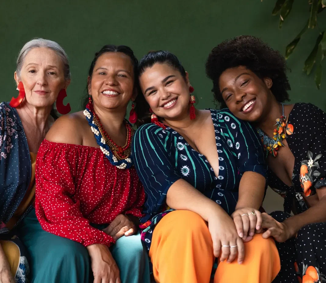 Four diverse women are sitting together looking at the camera with big smiles on their faces Some touch each others hands in solidarity. They are exited the learn more about Complementary and Alternative Medicine (CAM).